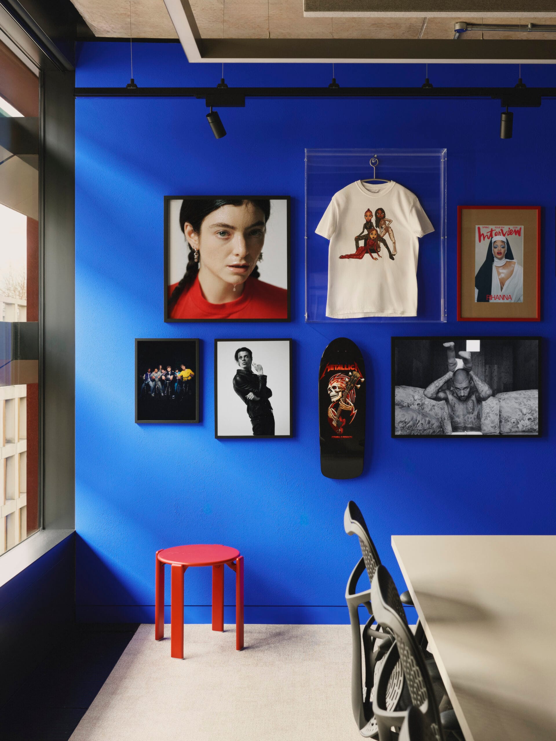 Een felblauwe wand in het EMI-kantoor met ingelijste foto's van artiesten, een skateboard en een ingelijst T-shirt