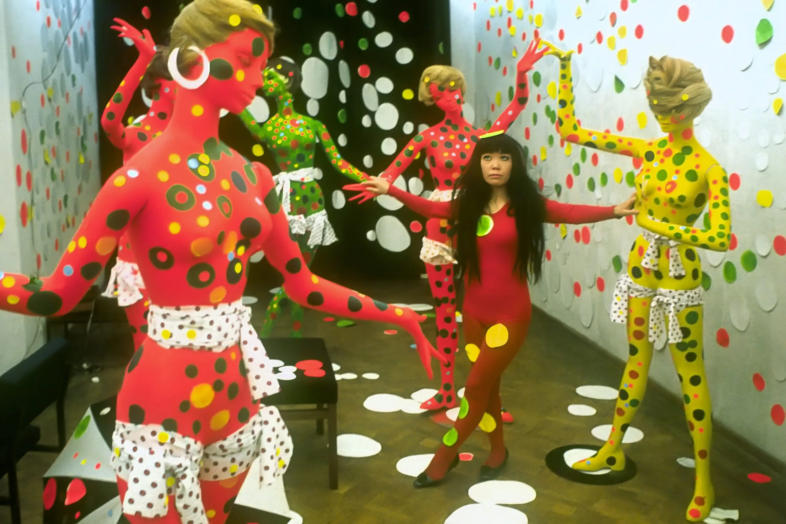 Yayoi Kusama poseert tussen kleurrijke paspoppen bedekt met stippen in een met stippen versierde ruimte, galerie Orez, Den Haag, 1967