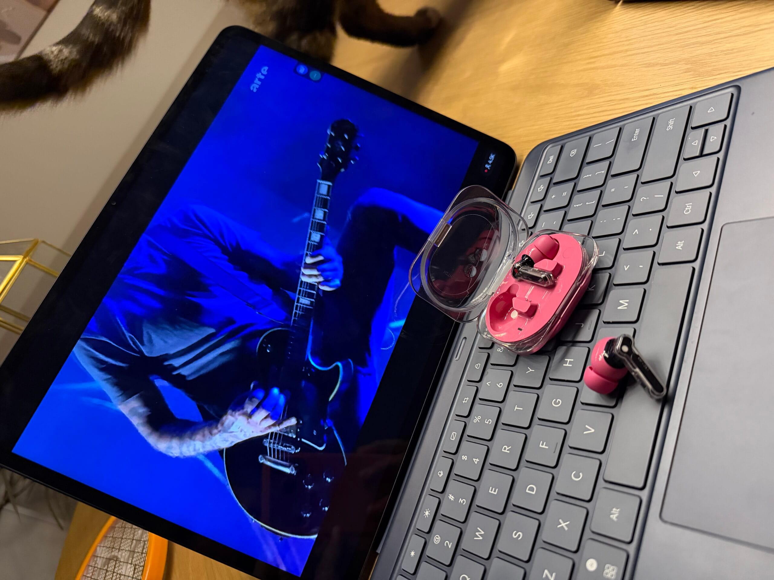 Roze Nothing Ear (3a) oortjes en een geopende transparante oplaadcase op het toetsenbord van een tablet