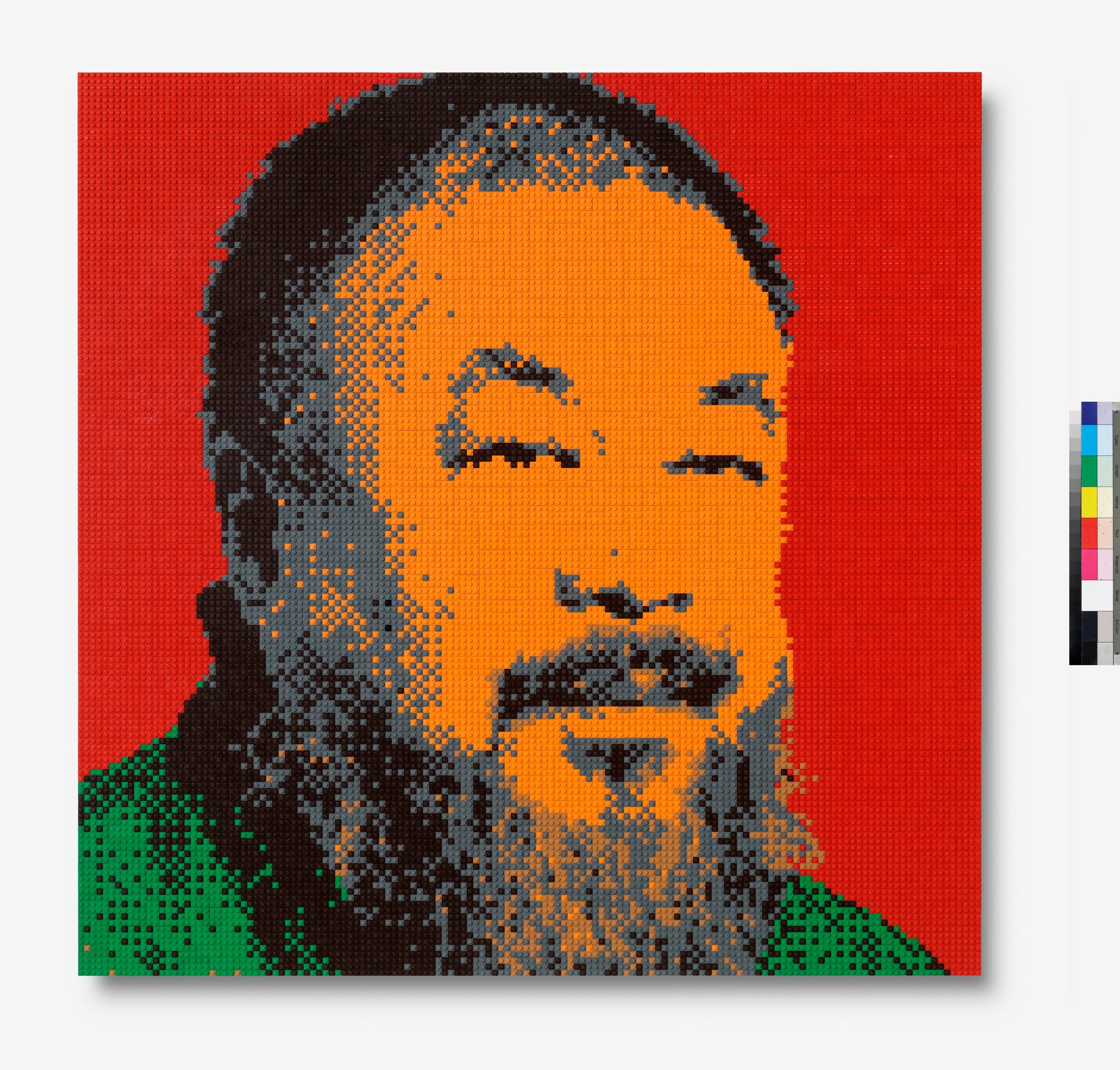Lego-mozaïek portret van Ai Weiwei in oranje-, grijs- en groentinten tegen een felrode achtergrond, het gaat om het werk Ai Weiwei in Red, 2022