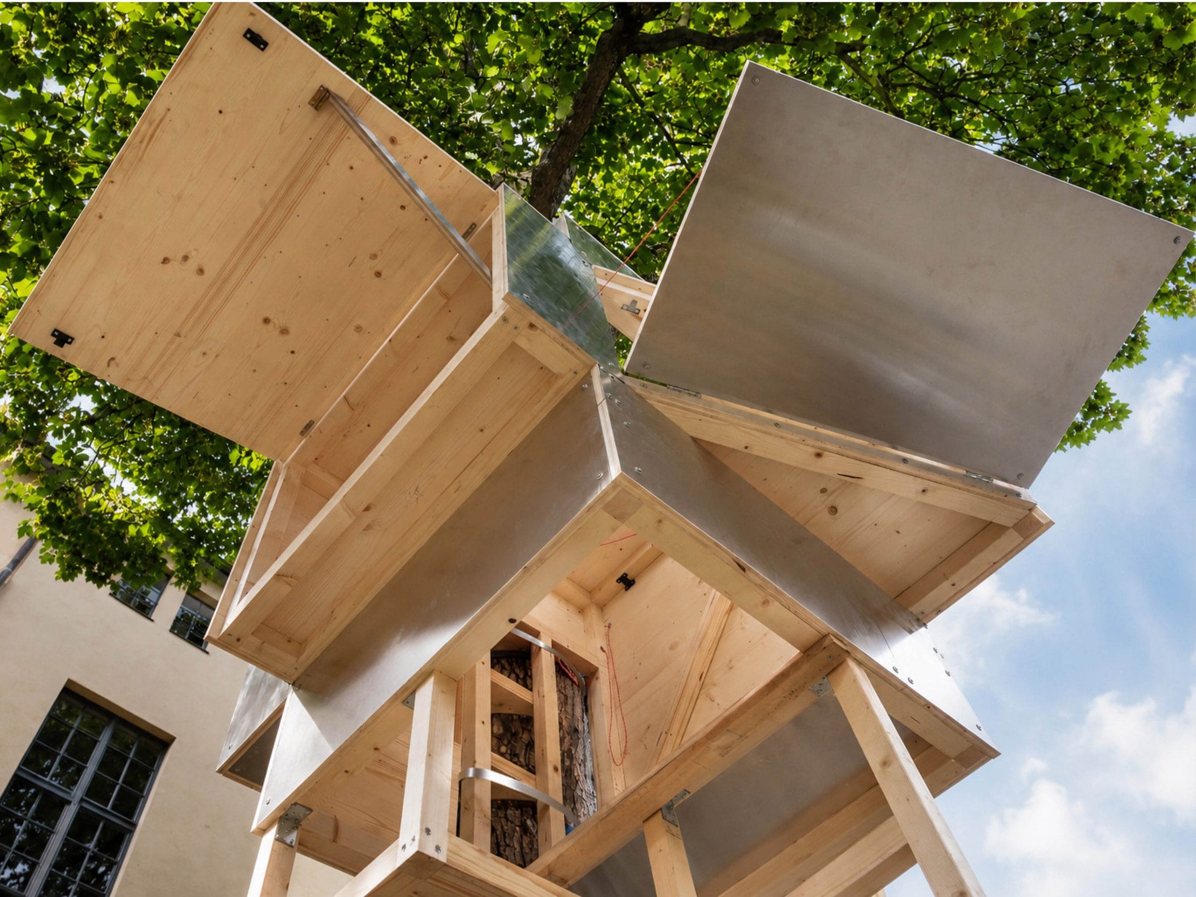 Onderaanzicht van het compacte houten en aluminium Baumhaus Office dat rondom een boomstam is gebouwd