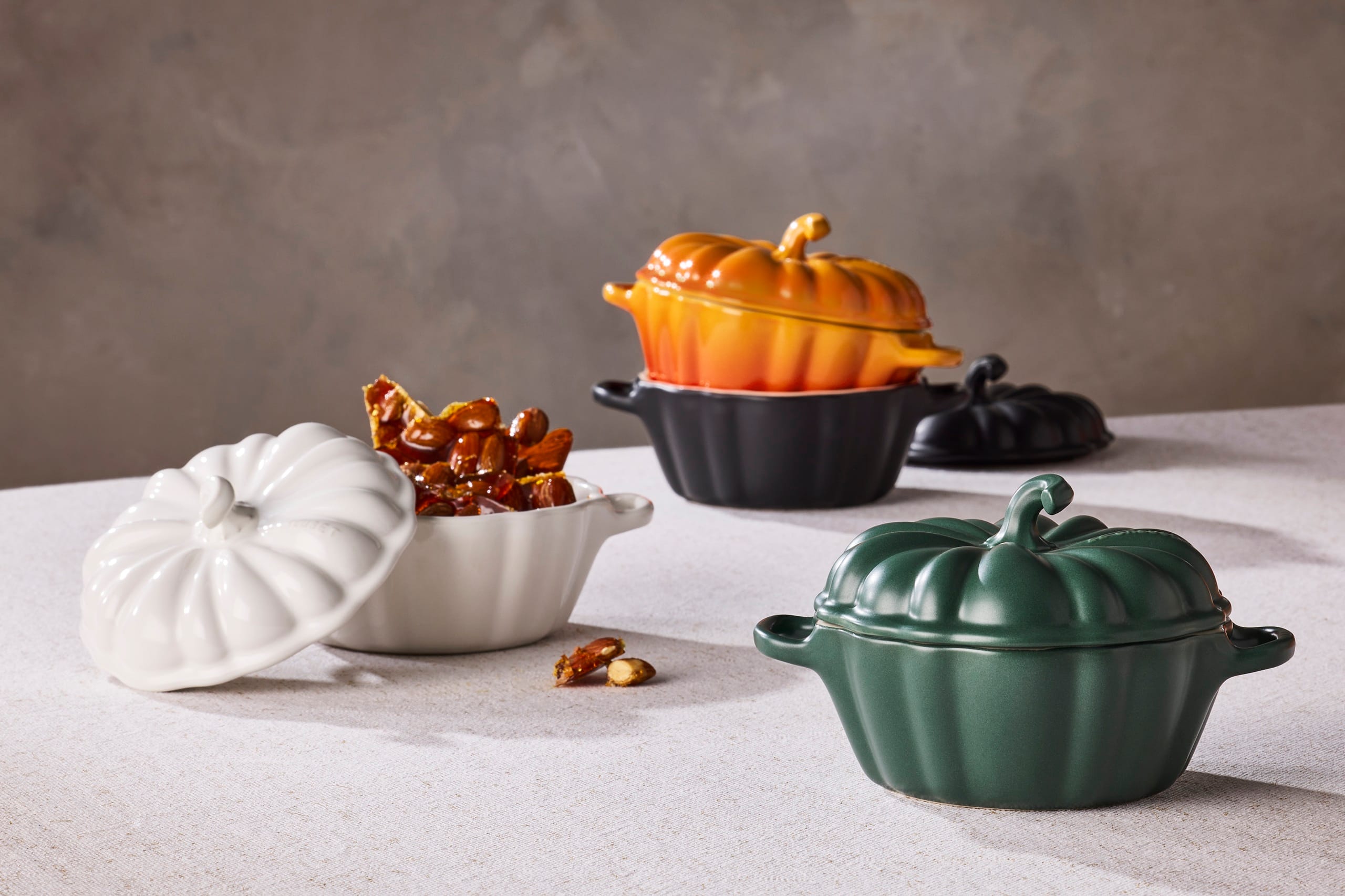 Pompoenvormige mini-stoofpotjes van Le Creuset in wit, groen, zwart en oranje op tafel