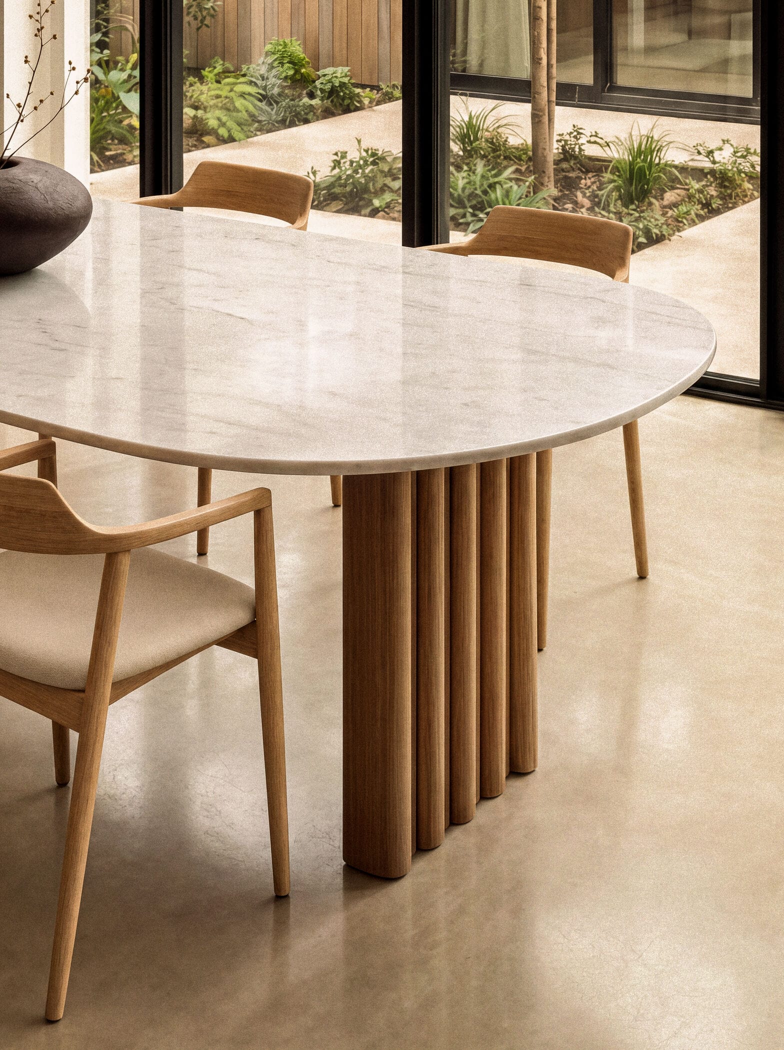 Ovale eettafel met een licht marmeren blad en geribbelde houten tafelpoot, omringd door houten eetkamerstoelen uit de collectie keramische tafels van Table du Sud