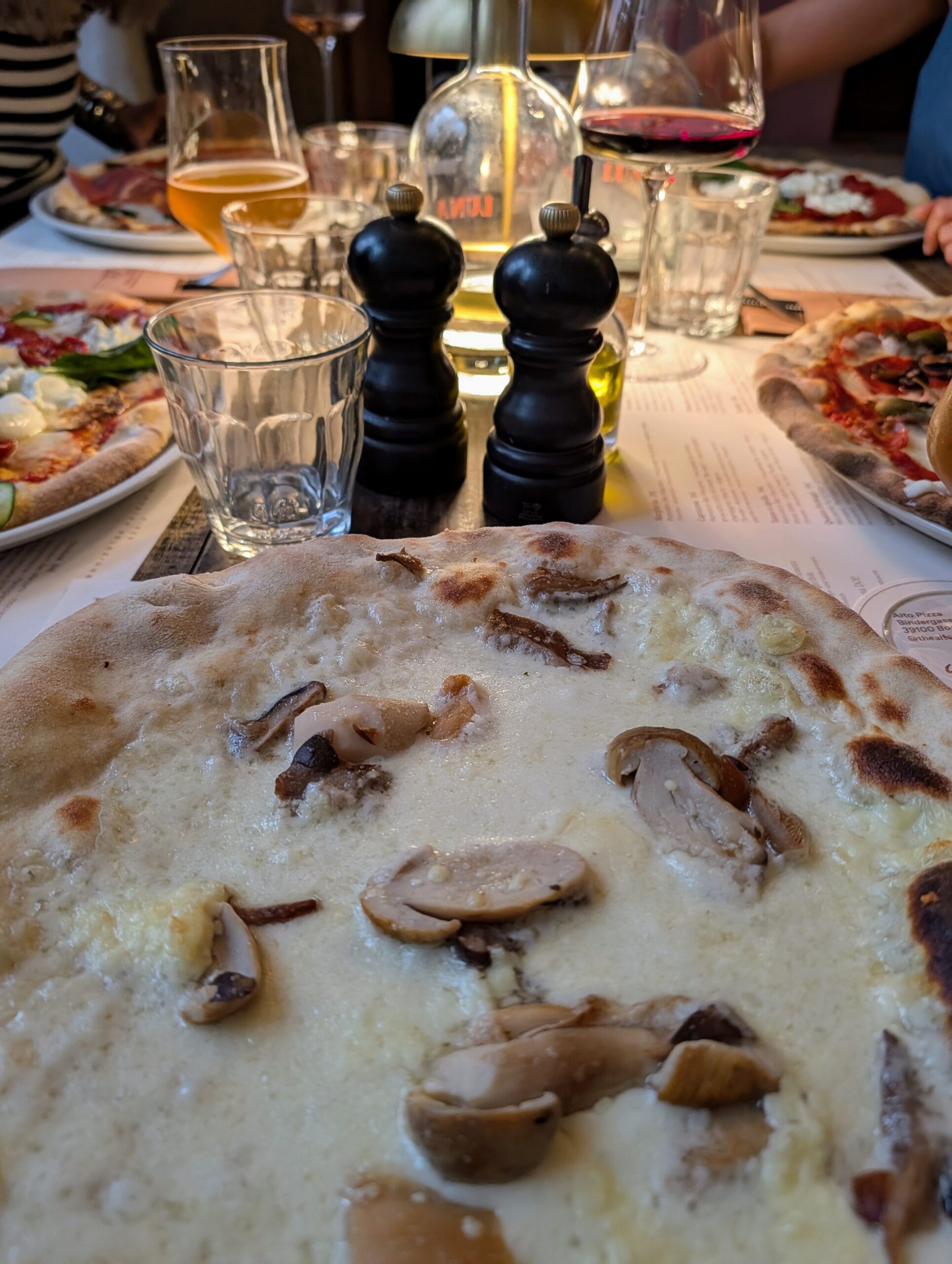 Zuurdesempizza met gesmolten kaas en paddenstoelen op een gedekte restauranttafel