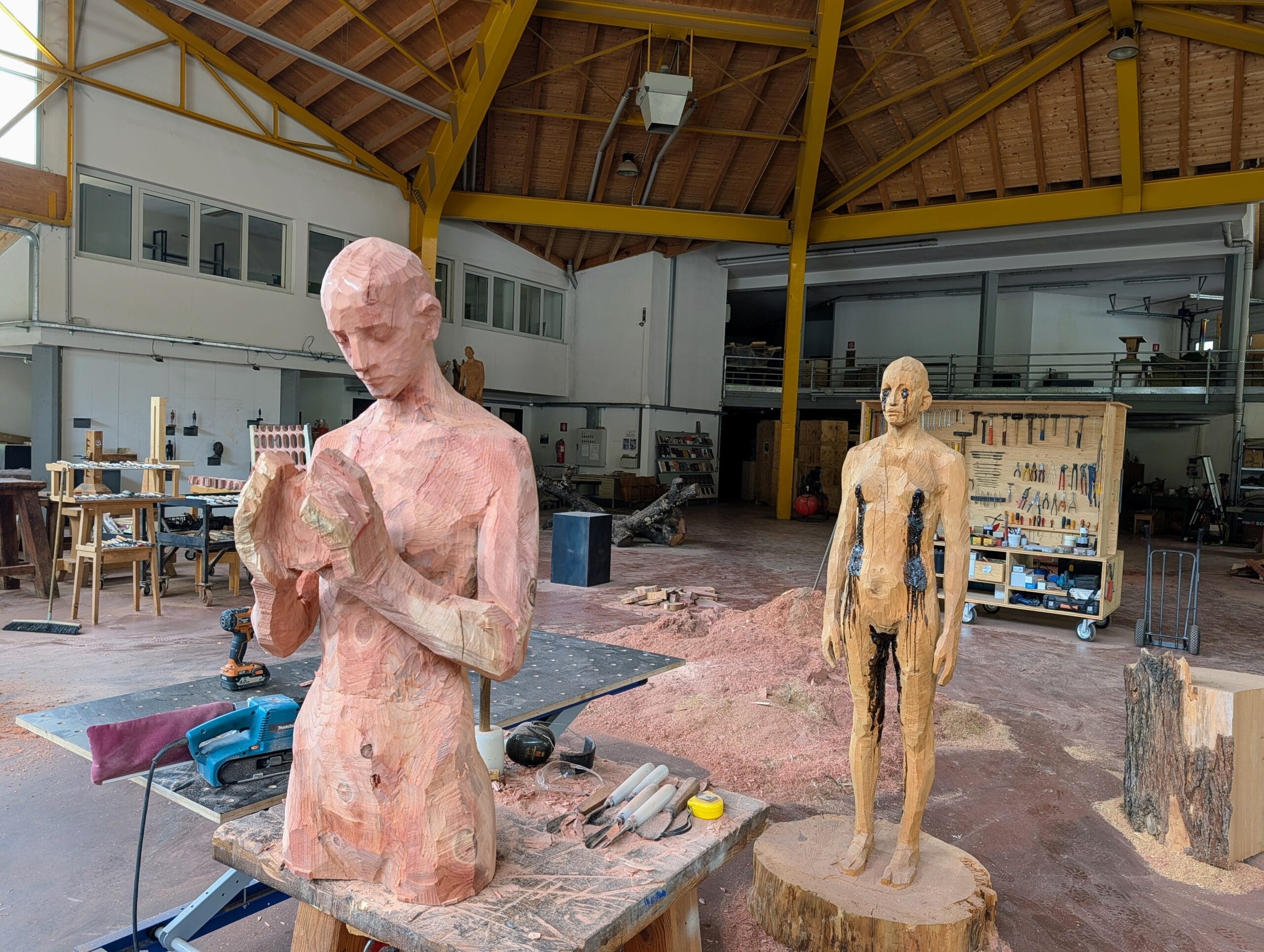 Houten sculpturen van mensfiguren in het ruime atelier van kunstenaar Aron Demetz