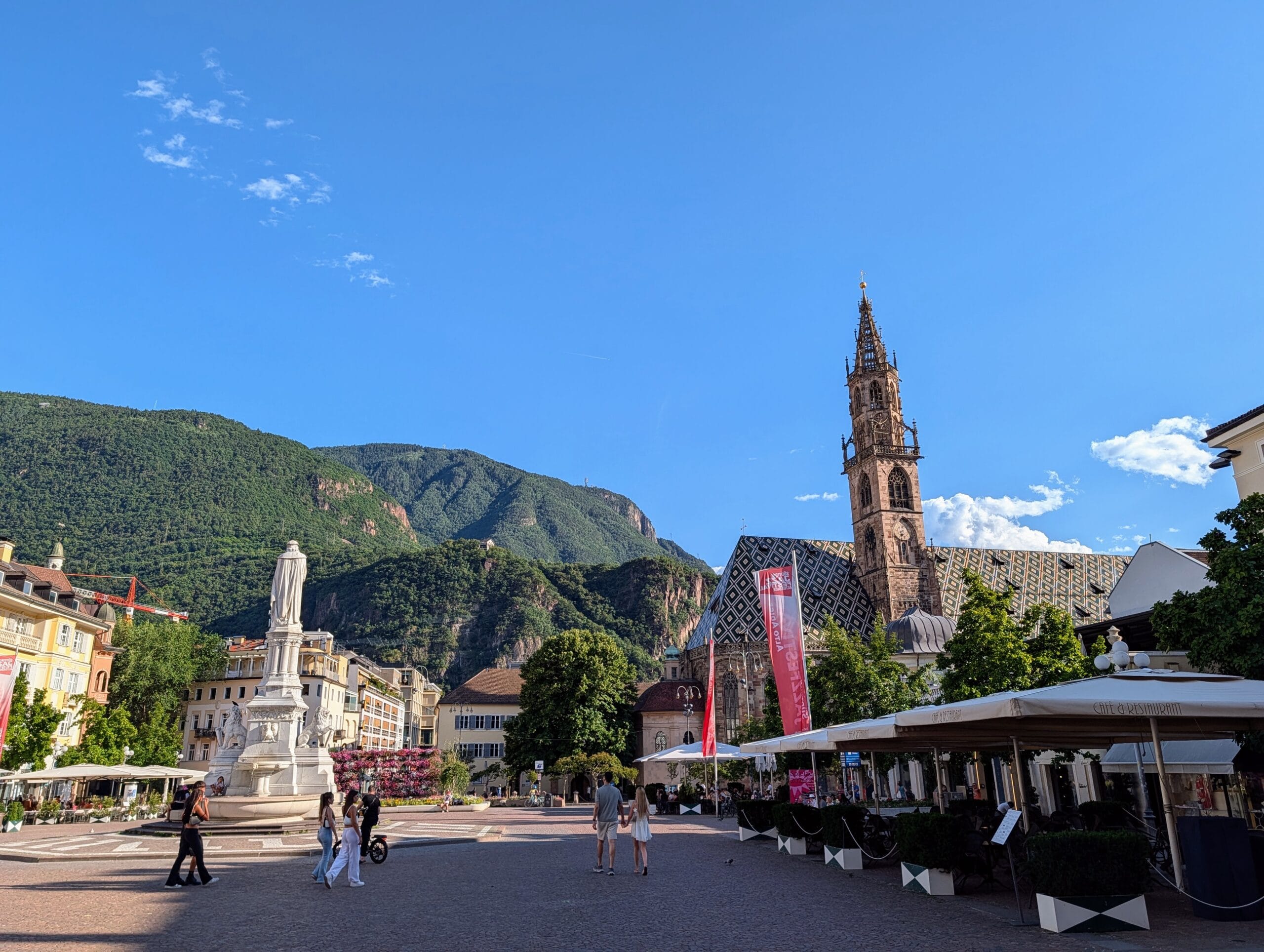 Waltherplatz in Bolzano met het standbeeld, de Dom Maria Himmelfahrt en de omliggende bergen op de achtergrond