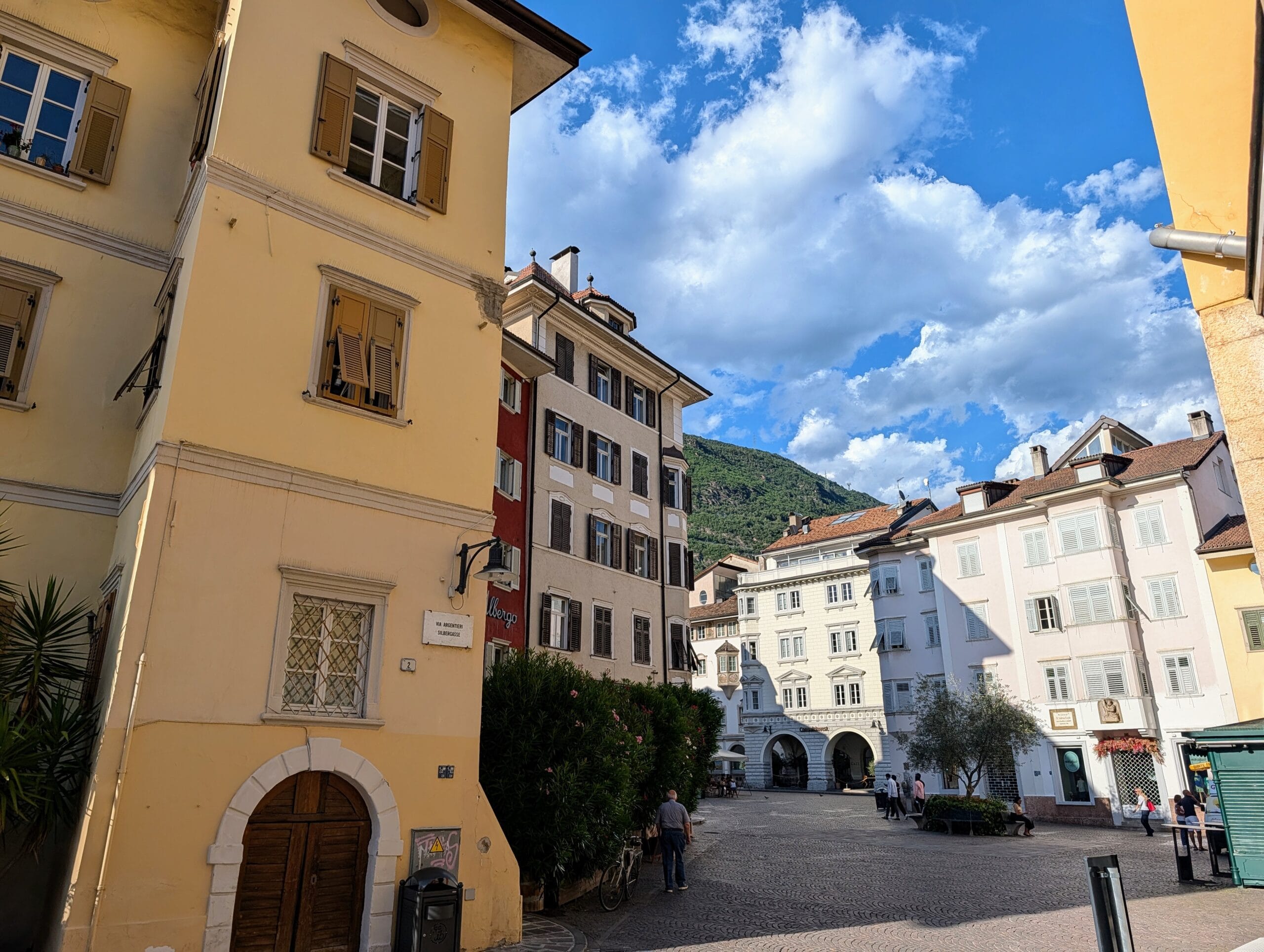 Plein in het centrum van Bolzano met pastelkleurige historische gebouwen en bergen op de achtergrond