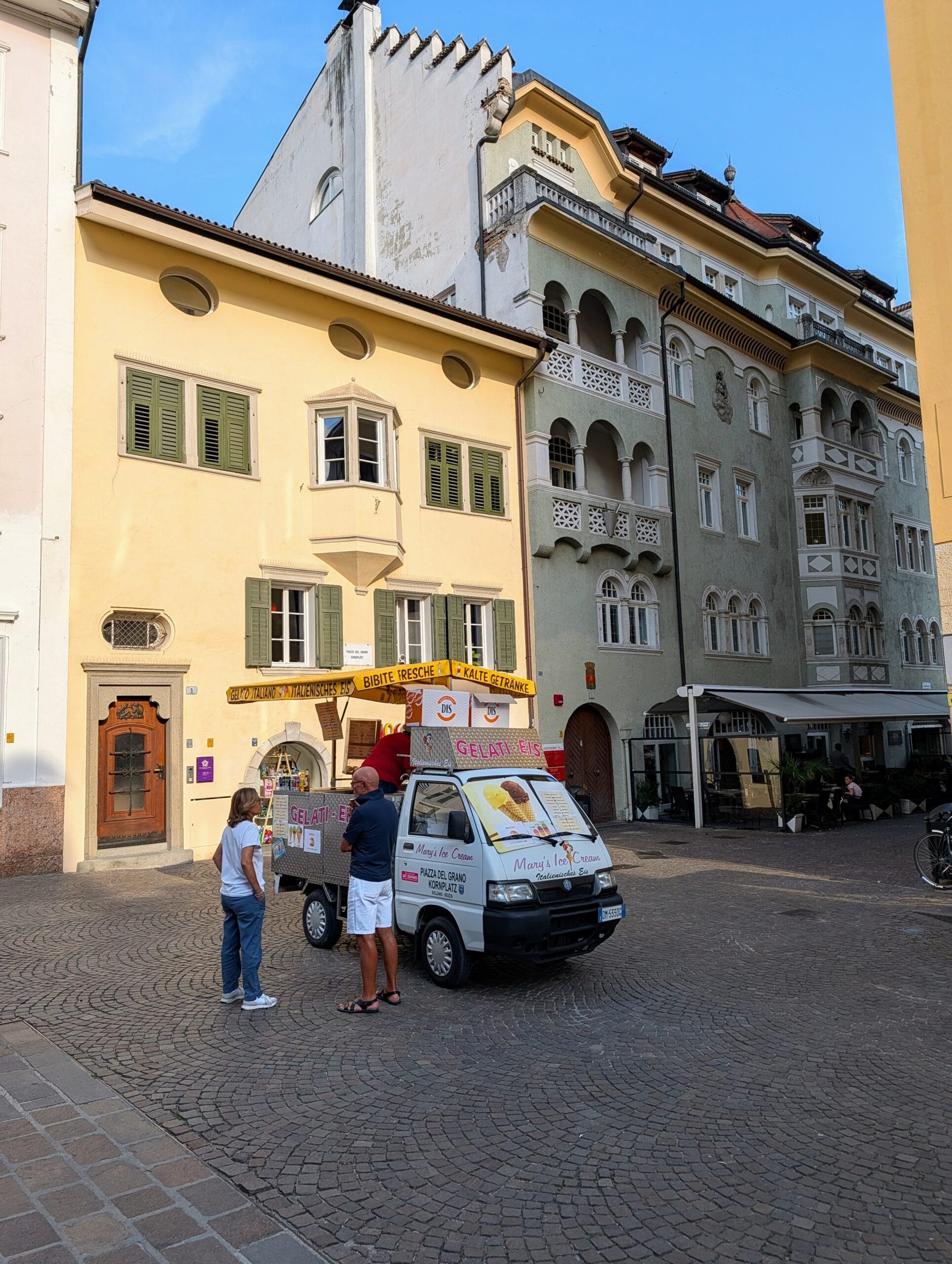 Een ijskarwagen op een geplaveid plein voor historische gebouwen in het centrum van Bolzano