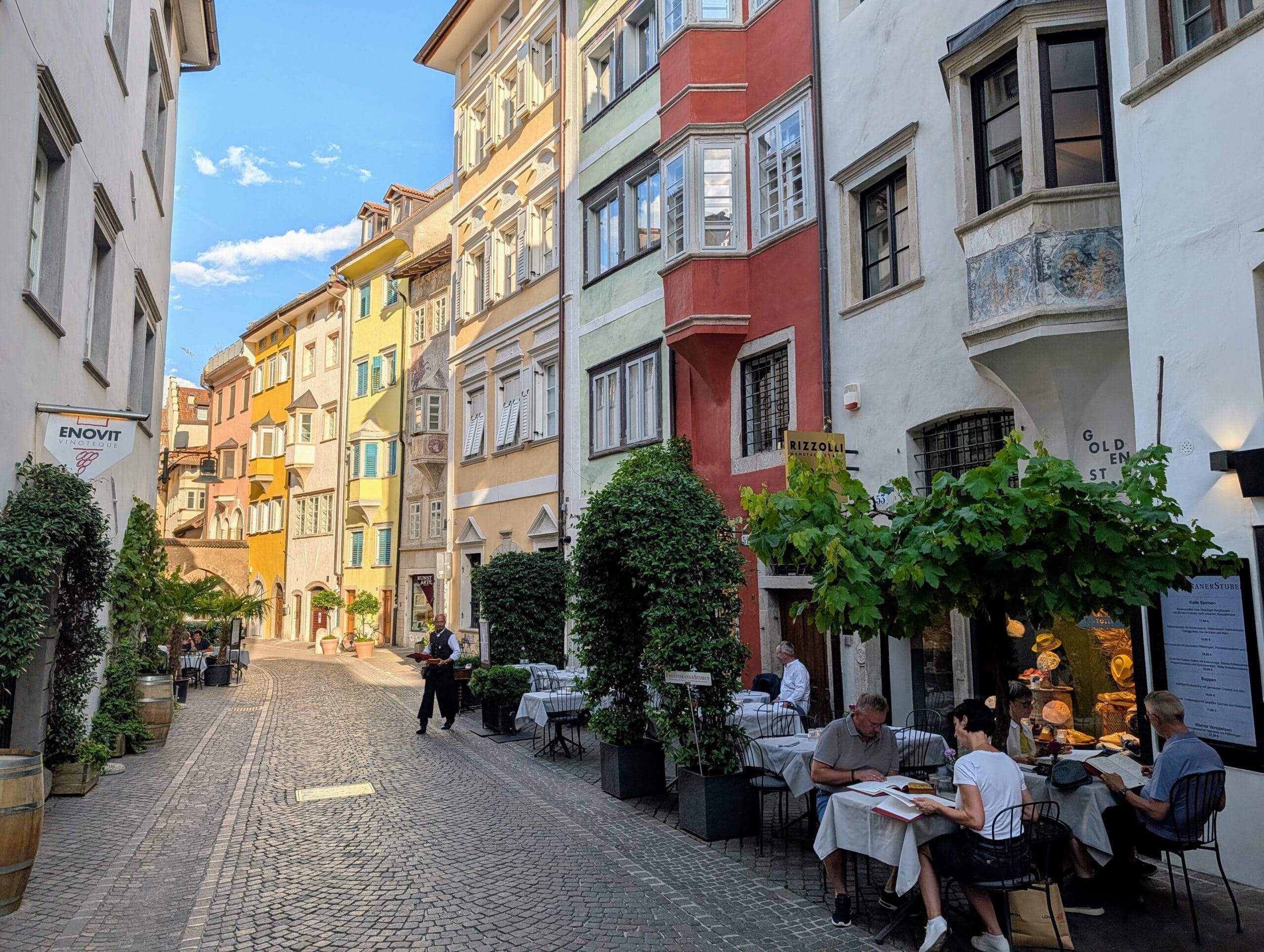 Kleurrijke, historische straat met kasseien en terrastafels van restaurants in het centrum van Bolzano
