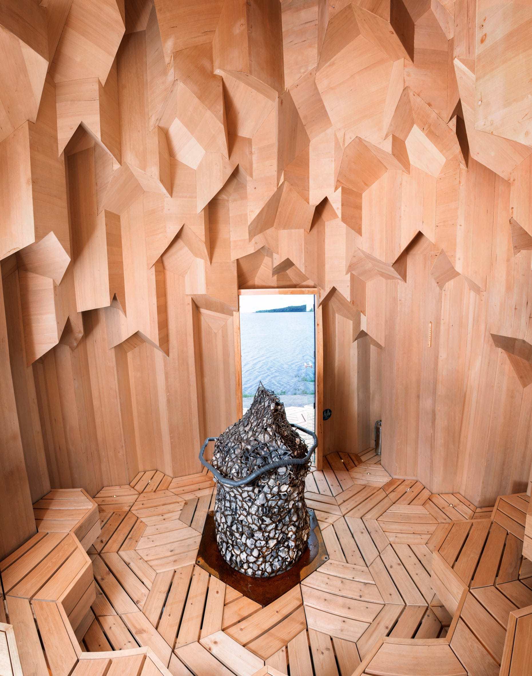 Houten interieur van de Lithium Crystal Sauna met geometrische wanden en een kachel in de vorm van een vuistbijl