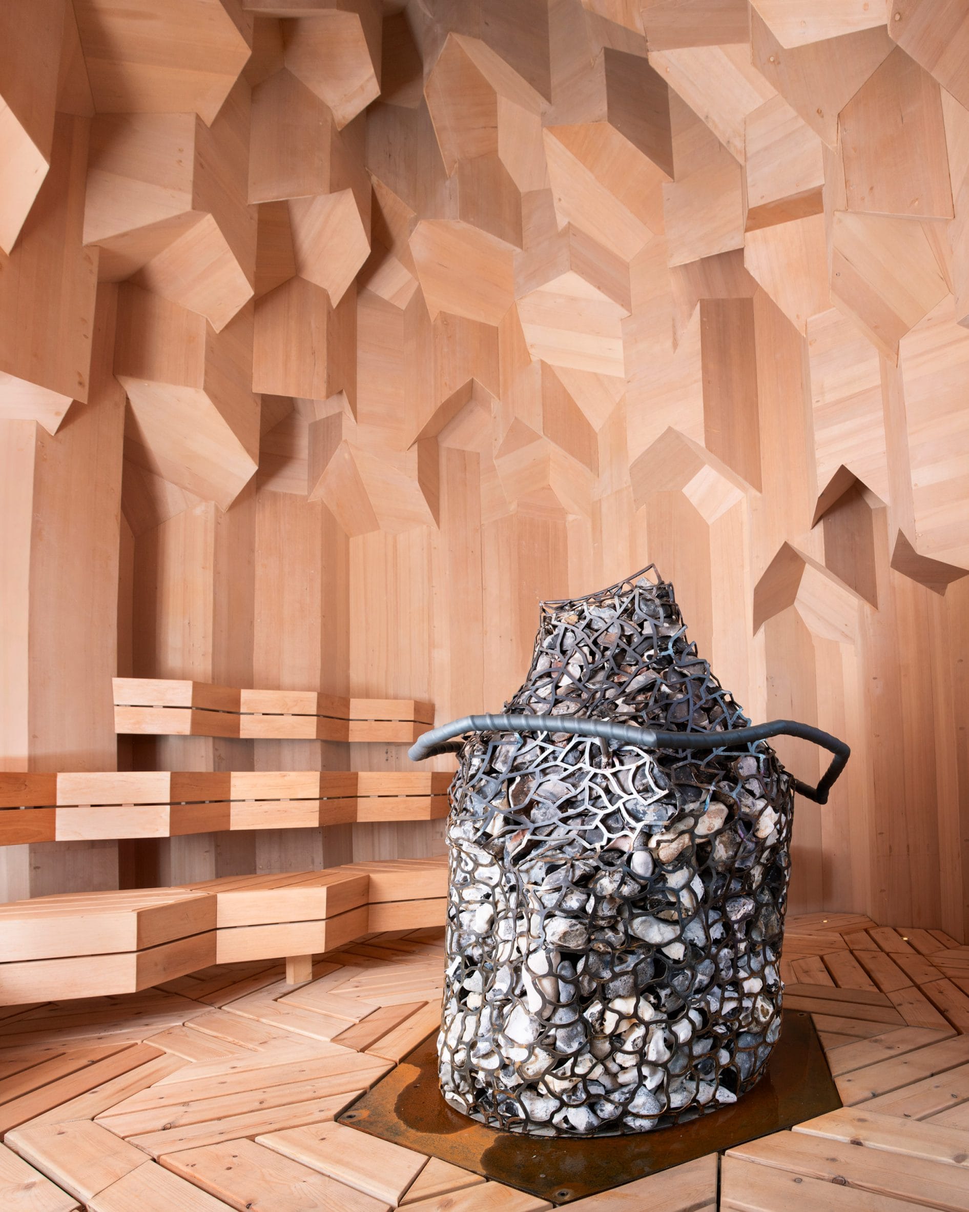 Houten interieur van de Lithium Crystal Sauna met geometrische wanden en een kachel in de vorm van een vuistbijl