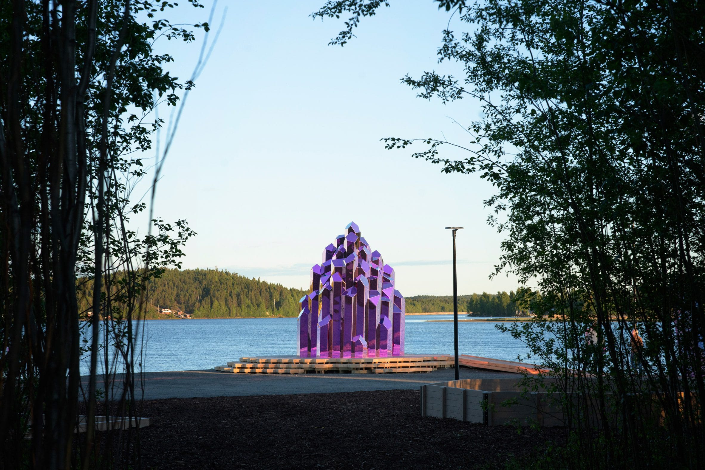 De roze, spiegelende Lithium Crystal Sauna in de vorm van een kristal aan de oever van de Skellefte-rivier