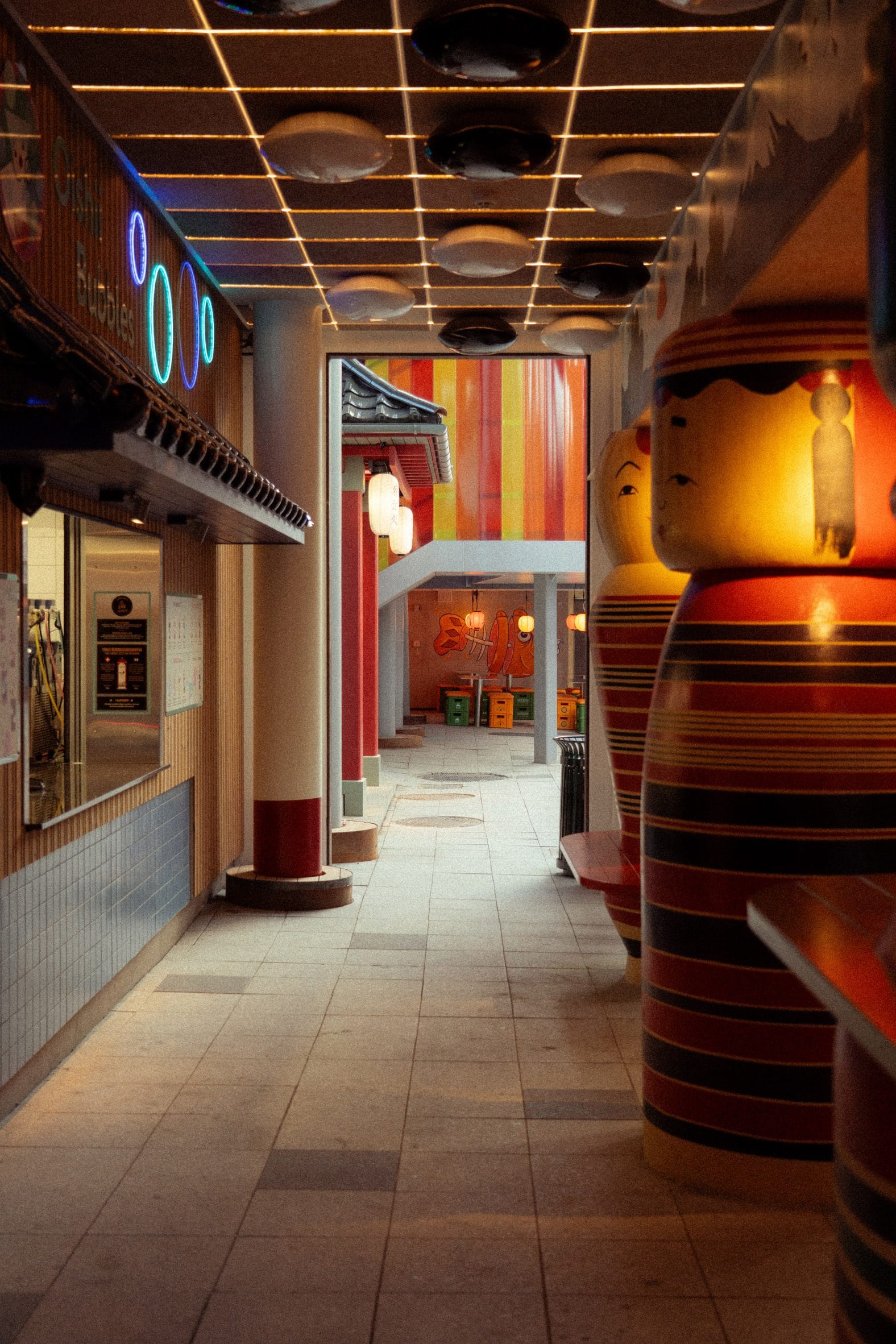 Sfeervol straatje in het themagebied Hikari met grote kokeshi-poppen, lampionnen en Japanse architectuur