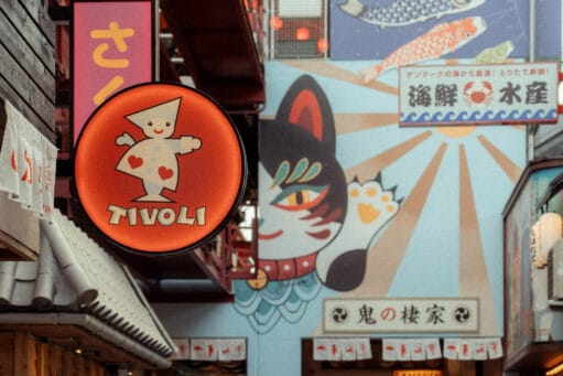 Winkelstraat in Japanse stijl met een oranje uithangbord van Tivoli en muurschilderingen van een kat en vissen