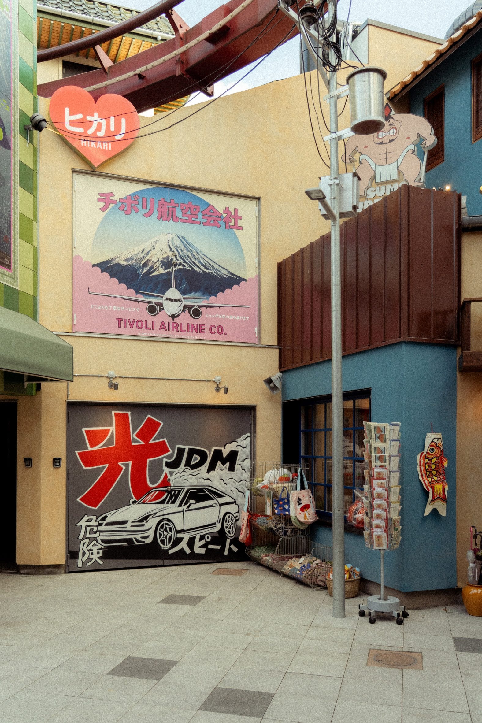 Japans straatbeeld in themagebied Hikari in Tivoli, met kleurrijke gevels, een Tivoli Airline-poster en muurkunst