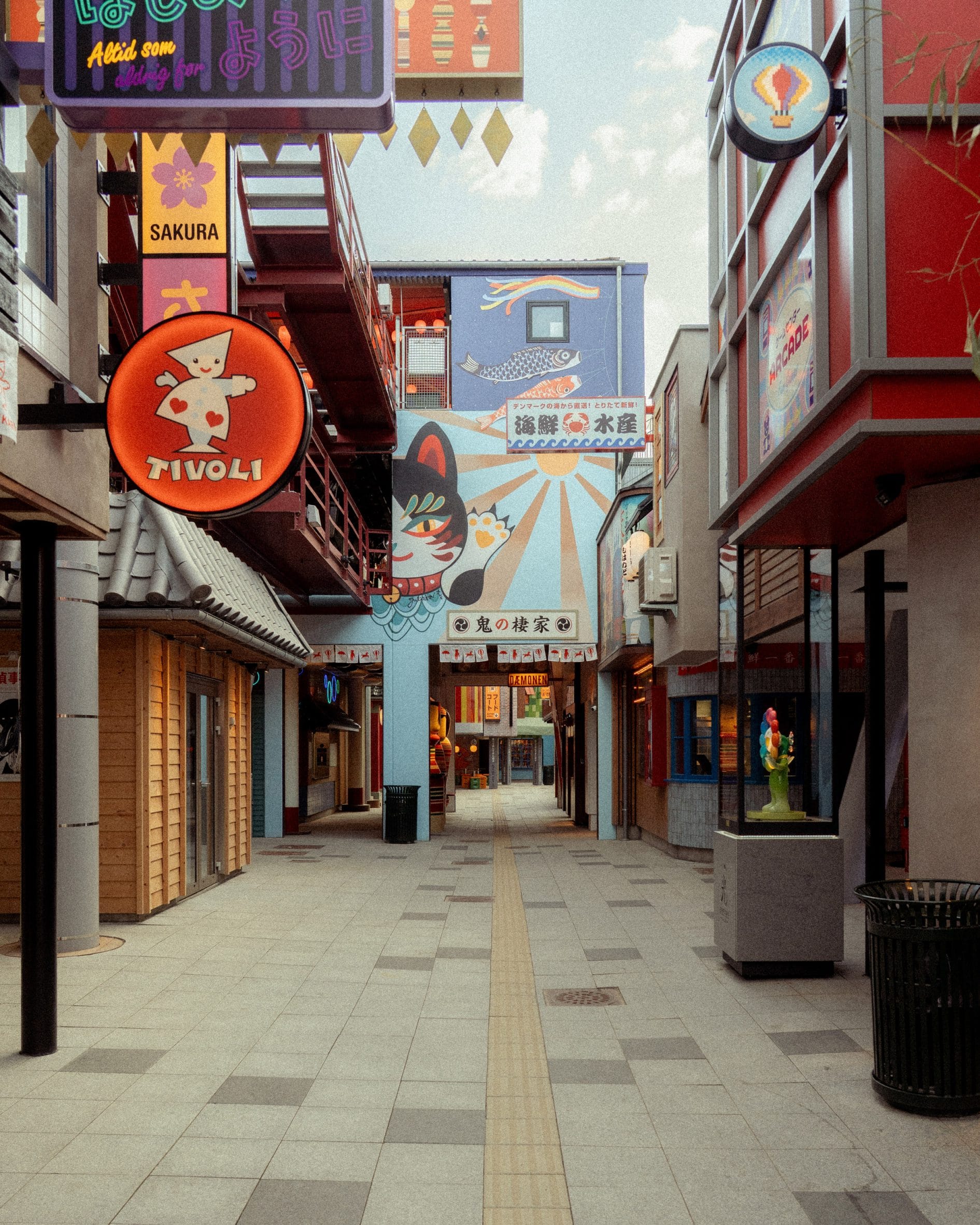 Winkelstraat in themagebied Hikari met Japanse uithangborden, gevels en een muurschildering van een gelukskat