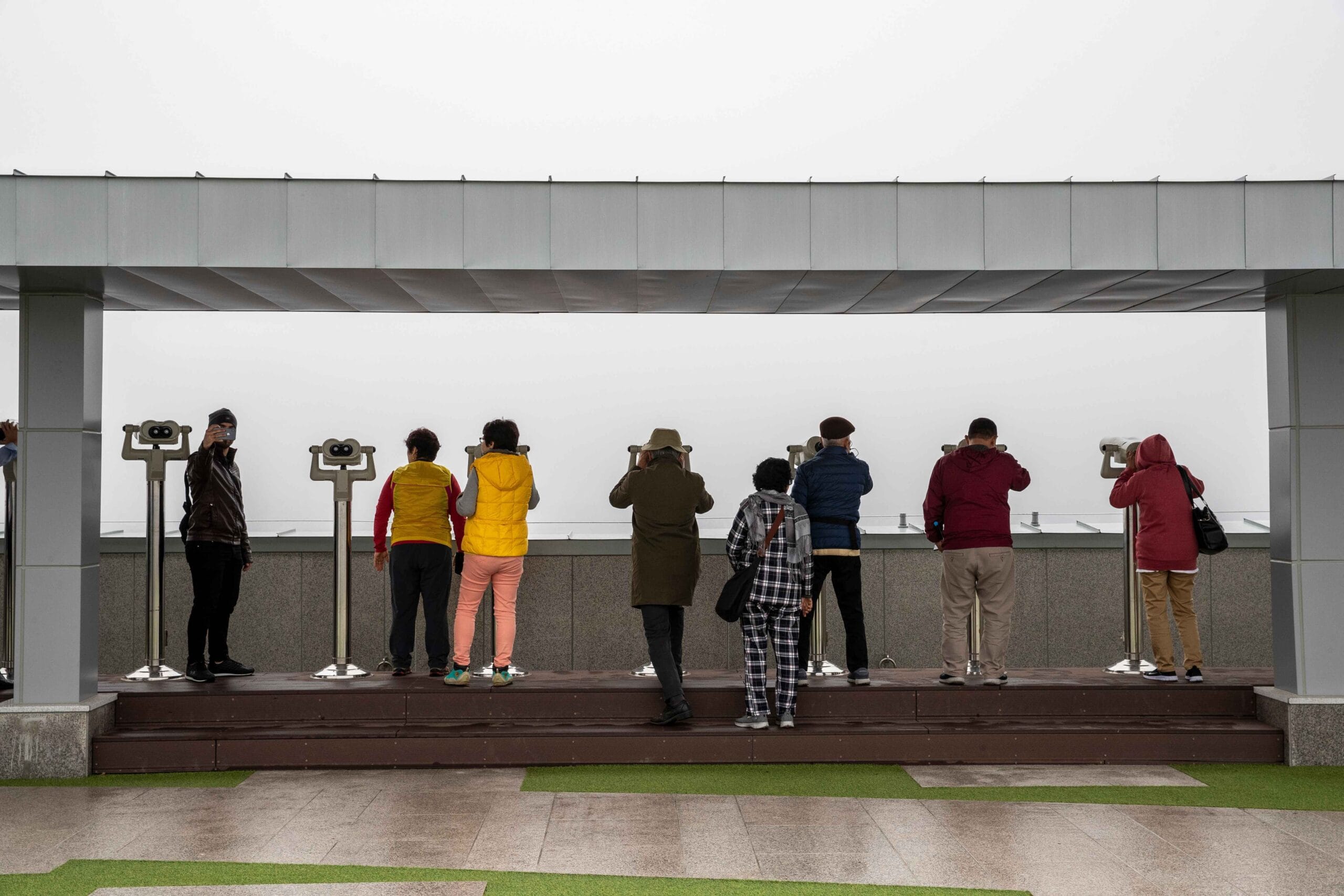 Bezoekers op het Dora Observatorium kijken door verrekijkers over de grens met Noord-Korea