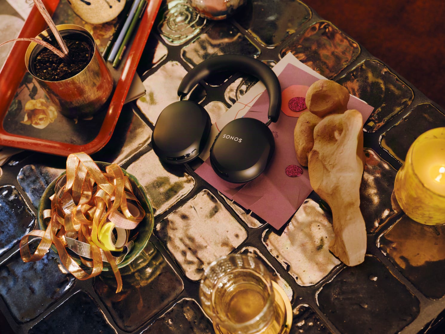 Zwarte Sonos Ace over-ear koptelefoon liggend op een betegelde tafel tussen decoratieve voorwerpen