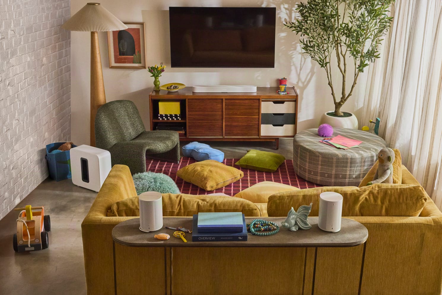 Witte Sonos Beam soundbar onder een tv, gecombineerd met een Sonos Sub en twee achterspeakers in een woonkamer
