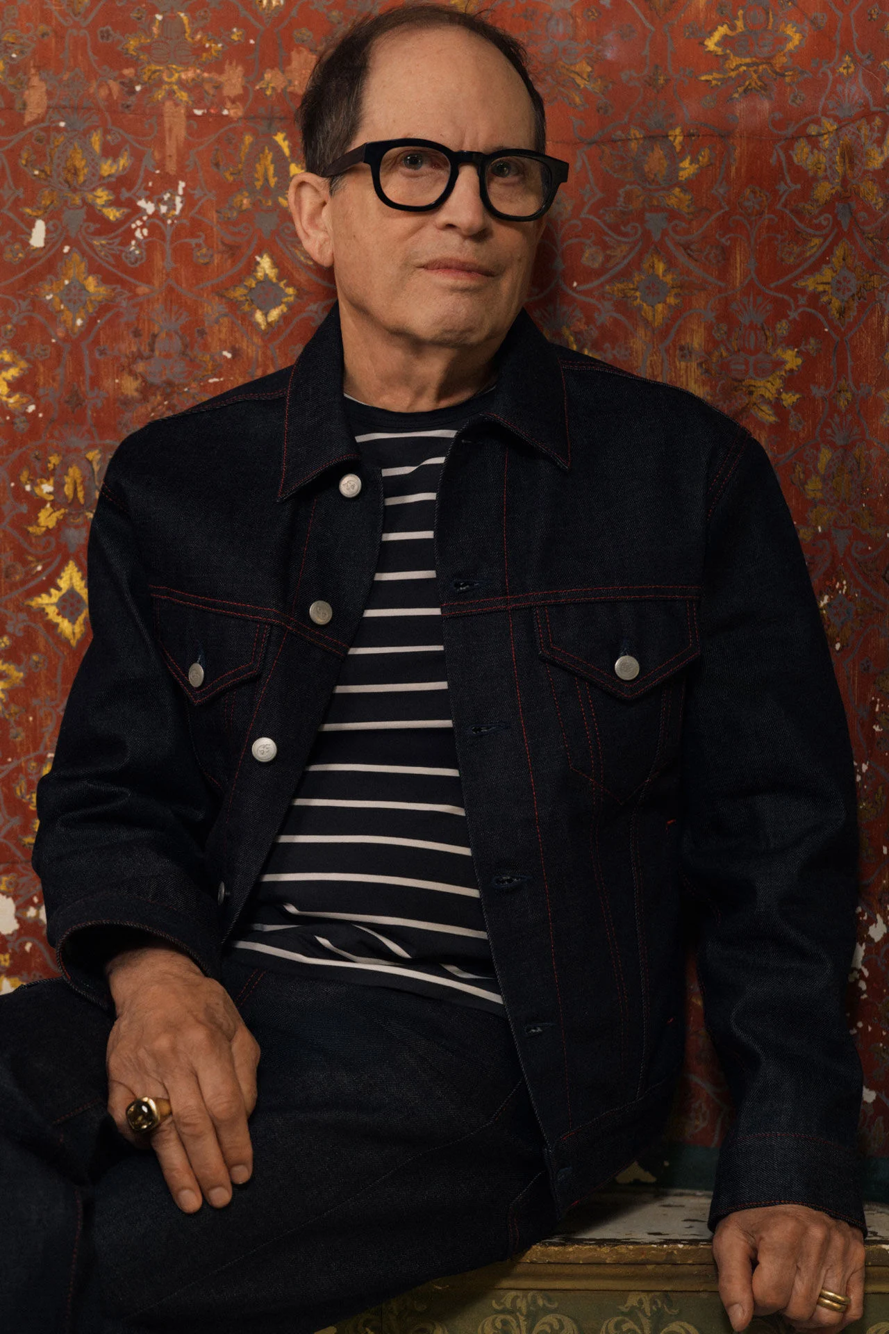 Portret van Peter Schlesinger in een donkerblauw denim jack met rood stiksel en een gestreept T-shirt