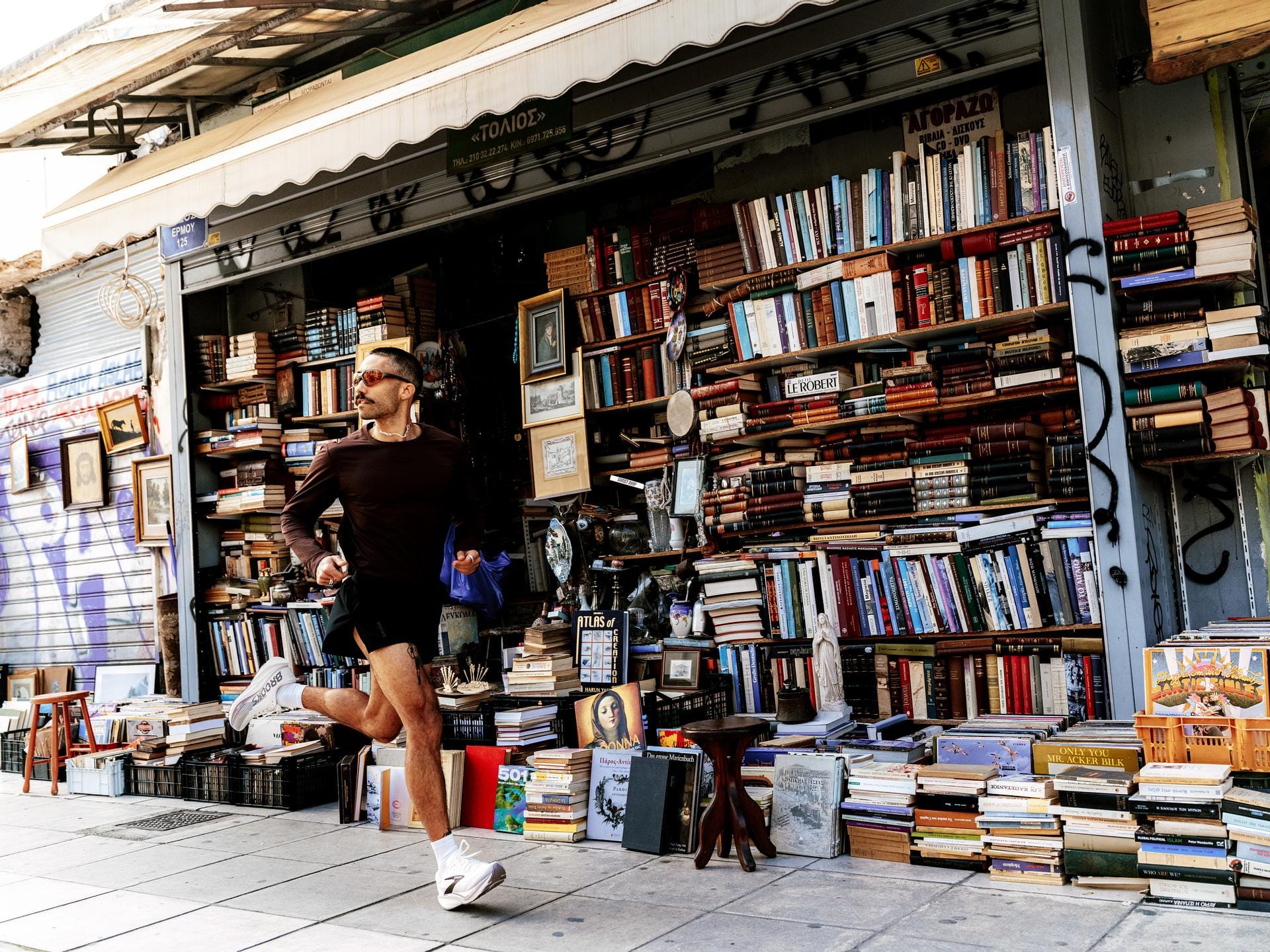 Hardloper rennend op Brooks hardloopschoenen langs een straat met een boekwinkel vol boekenstapels