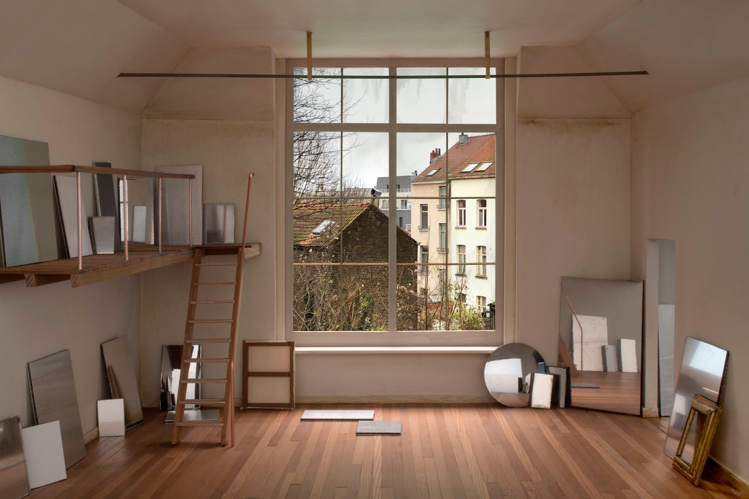 Schaalmodel van een kunstenaarsatelier met houten vloer, entresol en groot raam met uitzicht op Brusselse achtergevels
