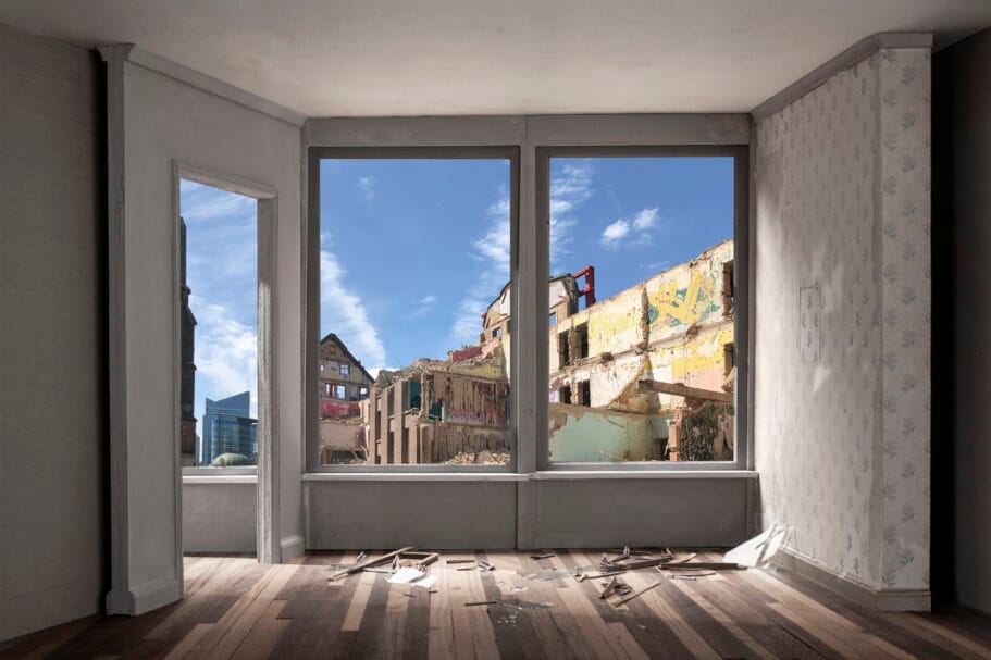 Uitzicht door het raam van een lege kamer op de ruïnes van een gesloopt gebouw