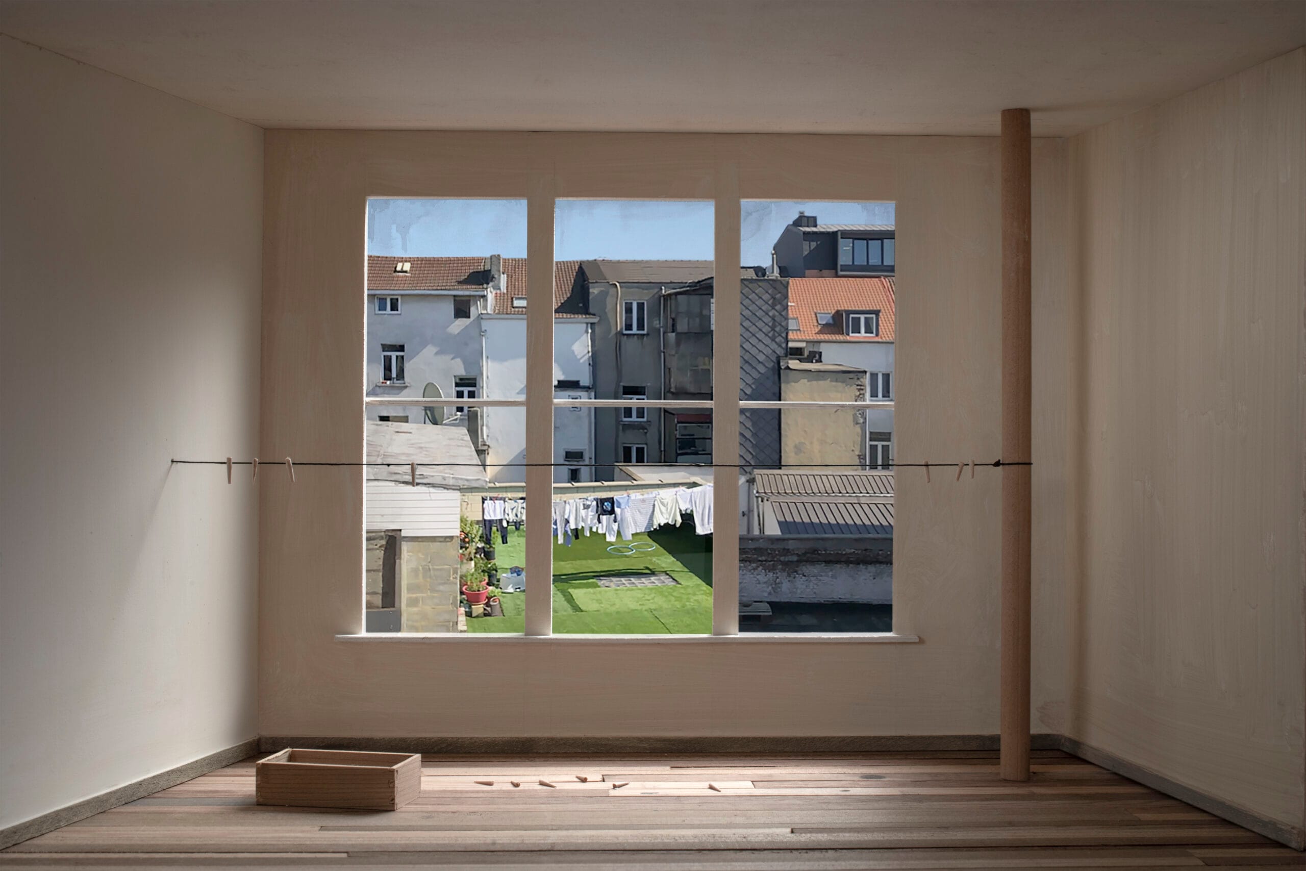 Foto van een sobere houten kamermaquette met uitzicht door het raam op Brusselse achtergevels en drogend wasgoed