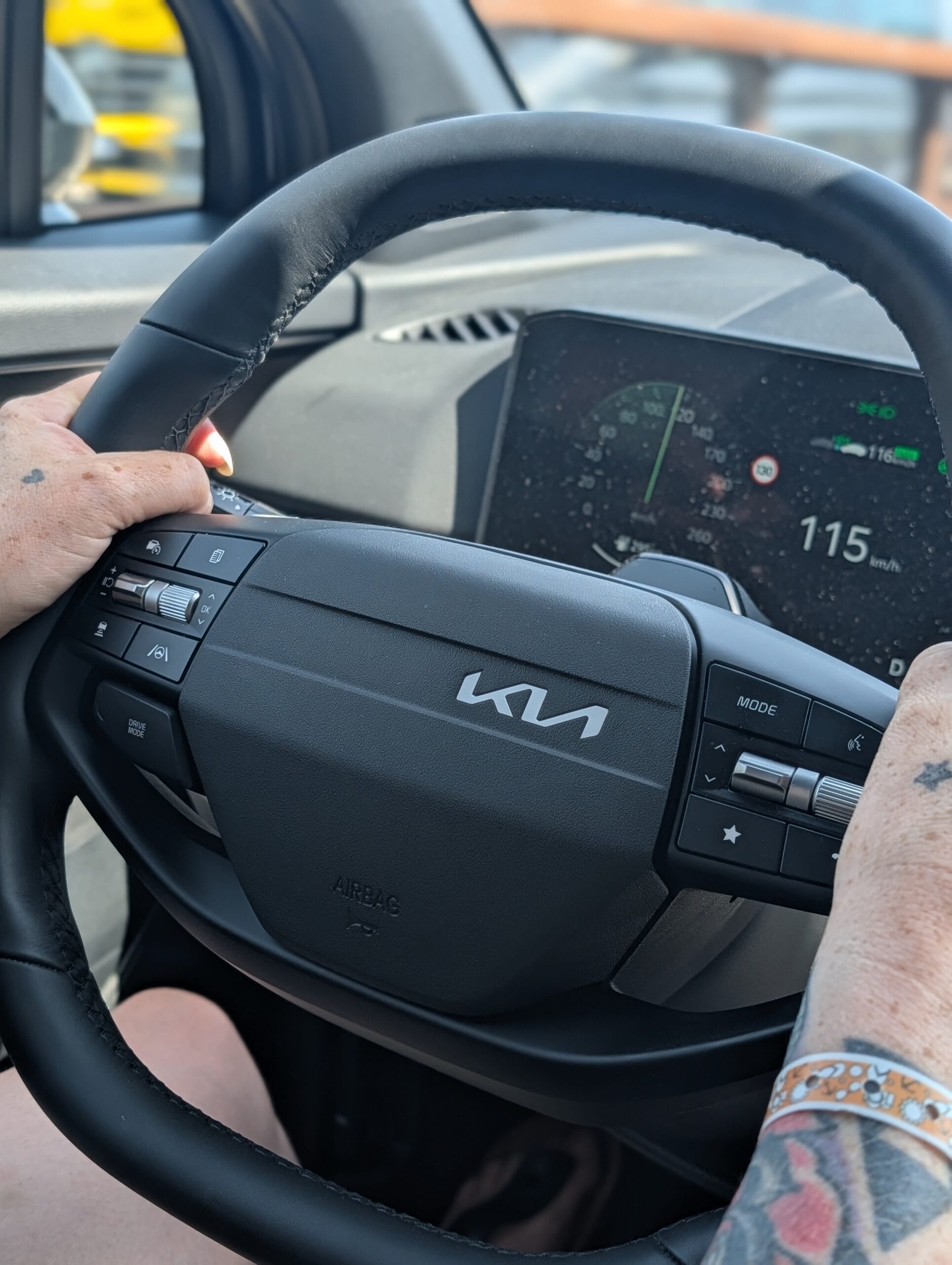 Bestuurder achter het stuur van de Kia Sportage met zicht op het digitale instrumentenpaneel tijdens het rijden