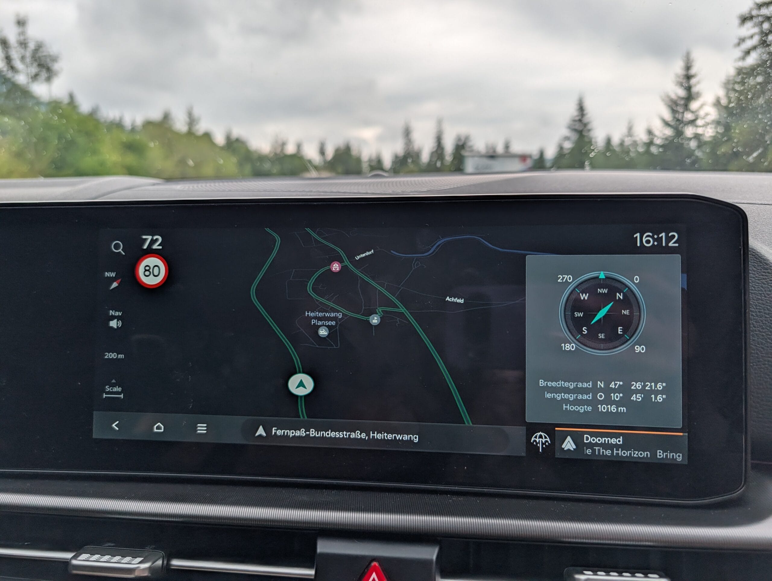 Infotainmentscherm van de Kia Sportage met navigatiekaart in donkere modus en een zijpaneel met digitaal kompas