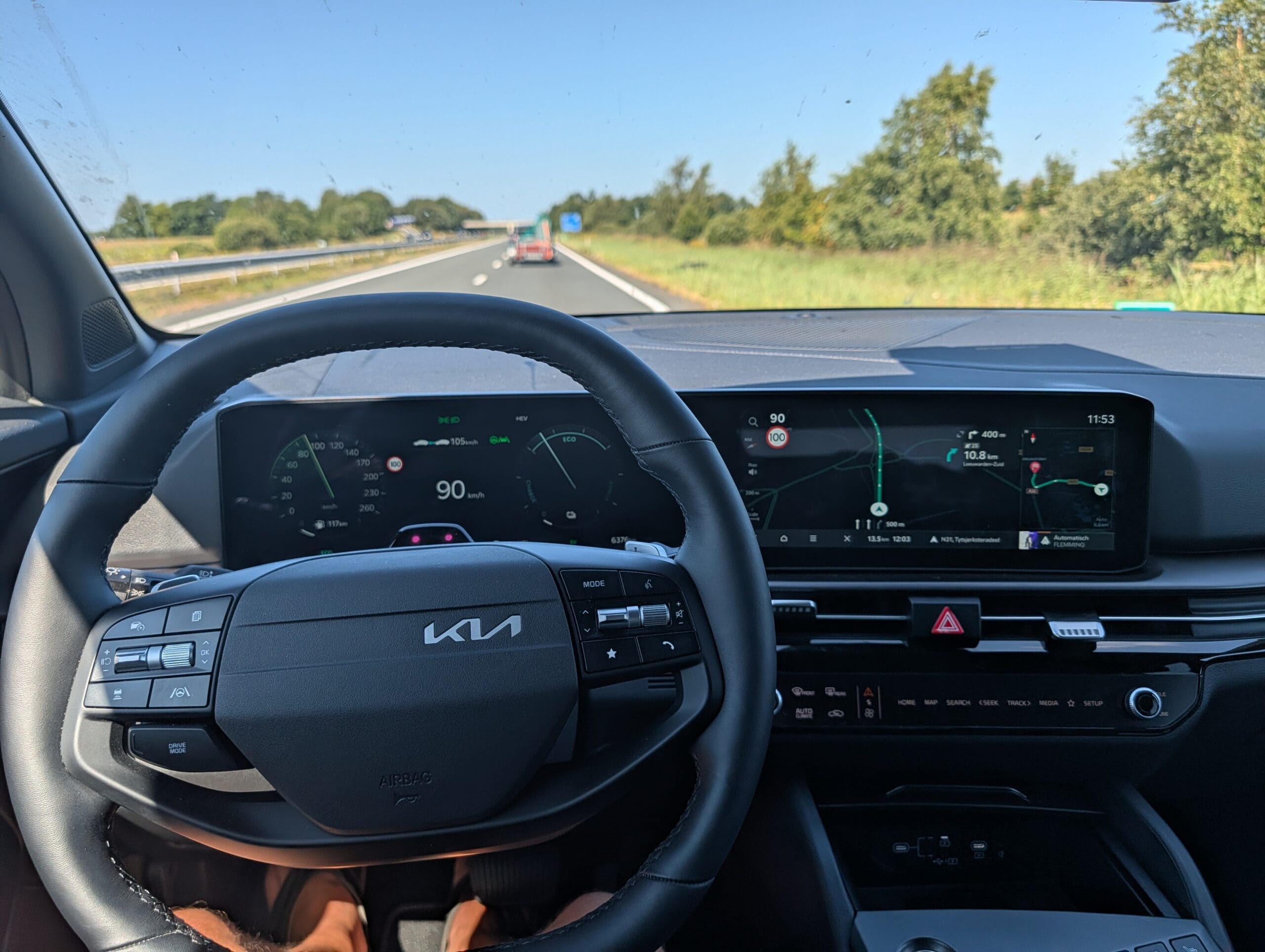 Zicht vanuit de Kia Sportage op het stuurwiel en het gebogen dashboard met digitale meters en navigatiescherm tijdens het rijden op de snelweg