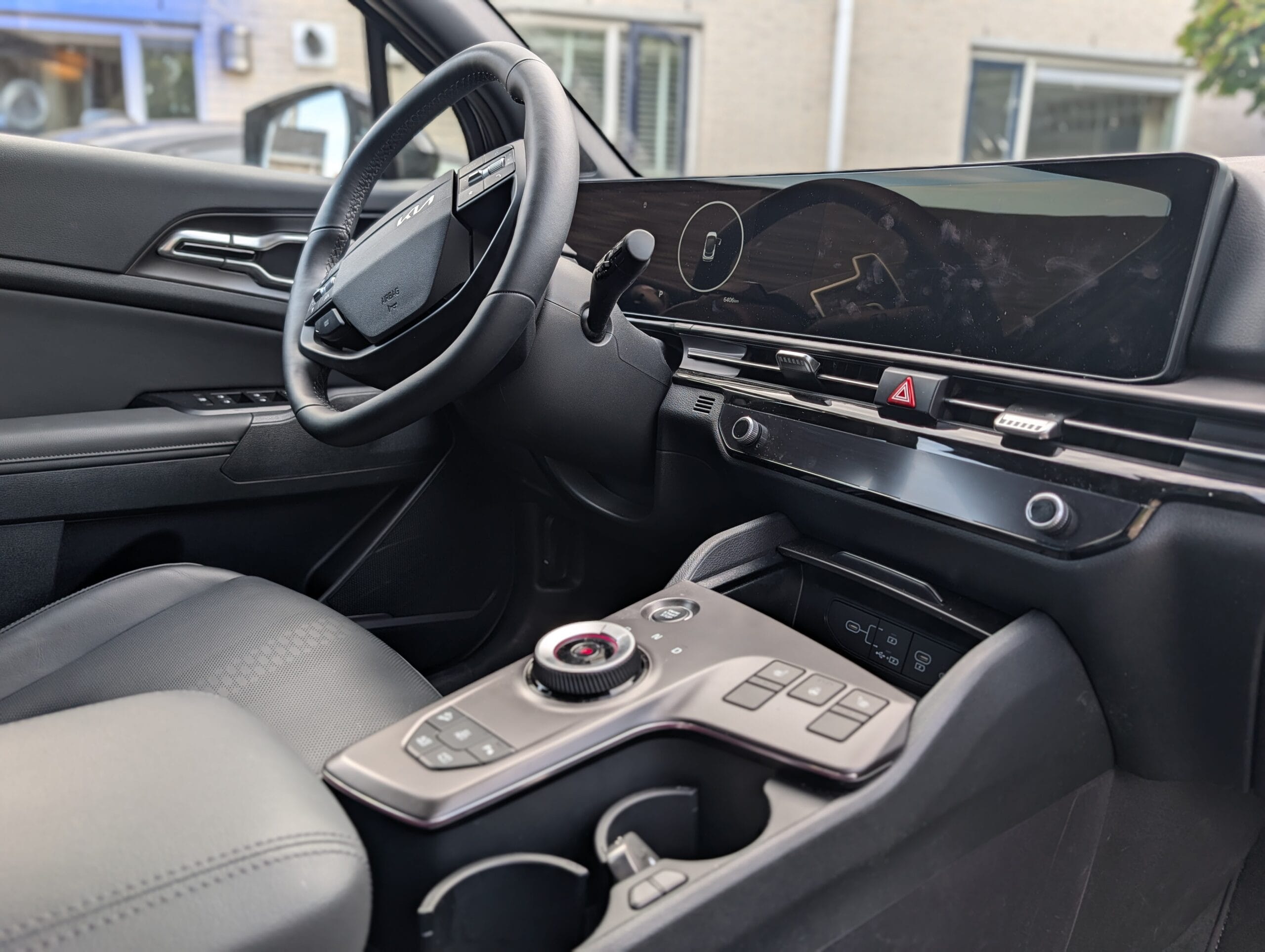 Interieur van de Kia Sportage met het stuurwiel, het brede gebogen schermpaneel en de middenconsole met draaiknop