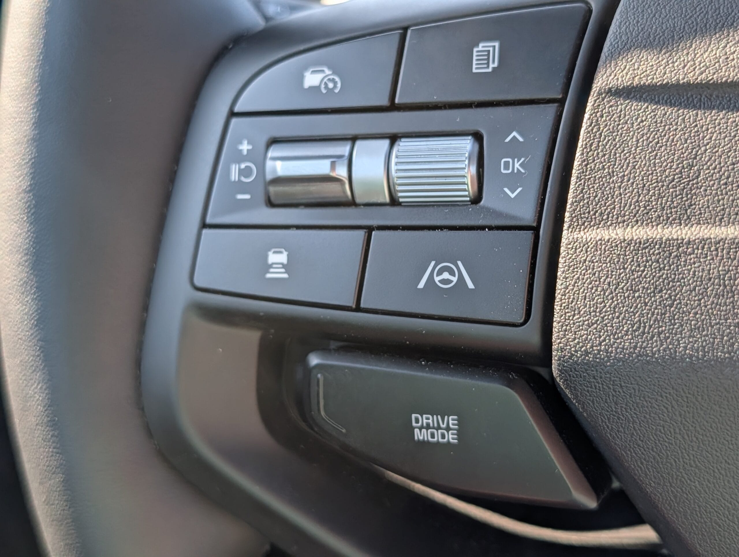 Stuurwielbediening van de Kia Sportage met knoppen voor cruise control, lane assist en de Drive Mode-knop