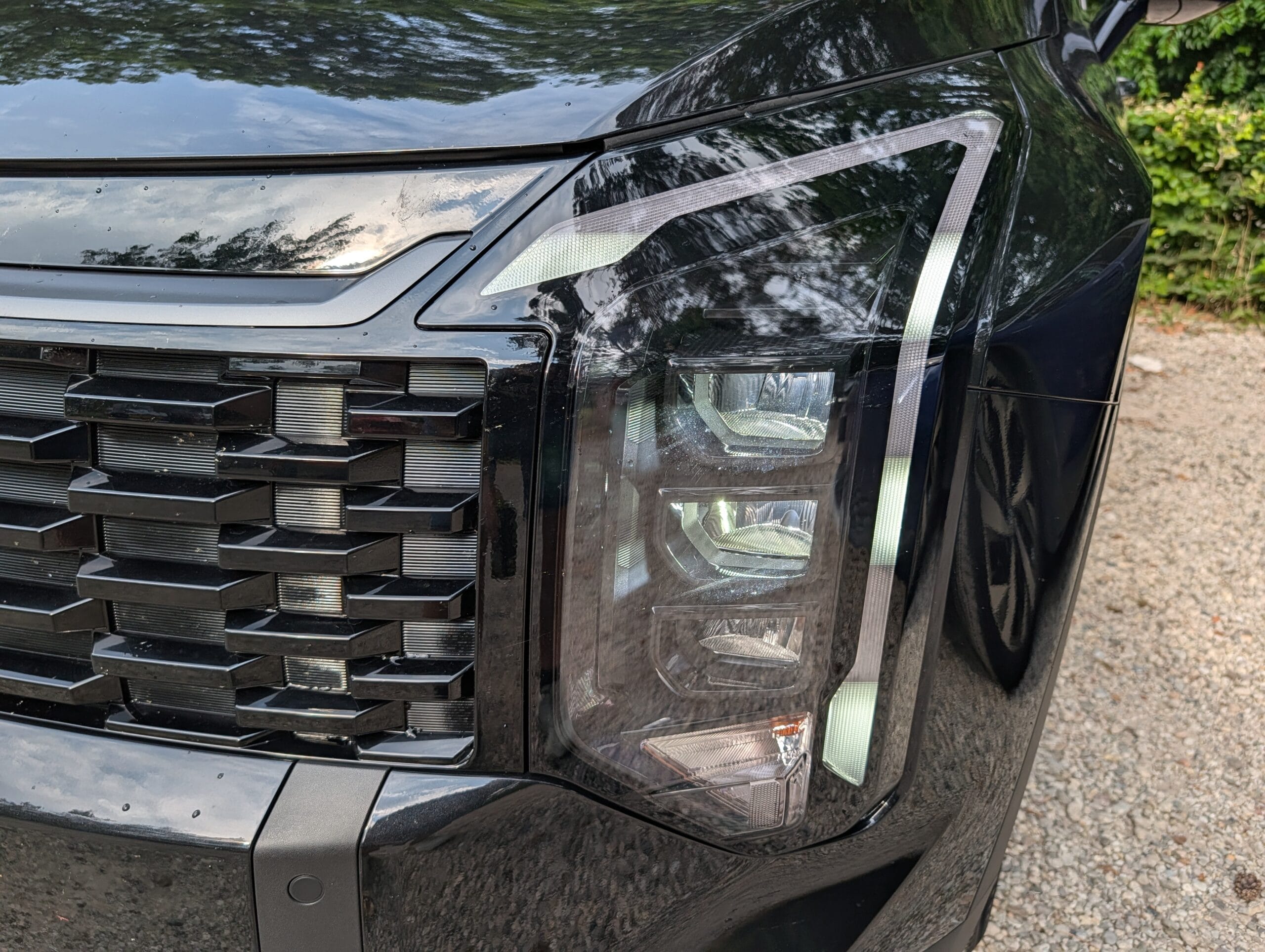 Detail van de zwarte grille en de koplampunit van de zwarte Kia Sportage