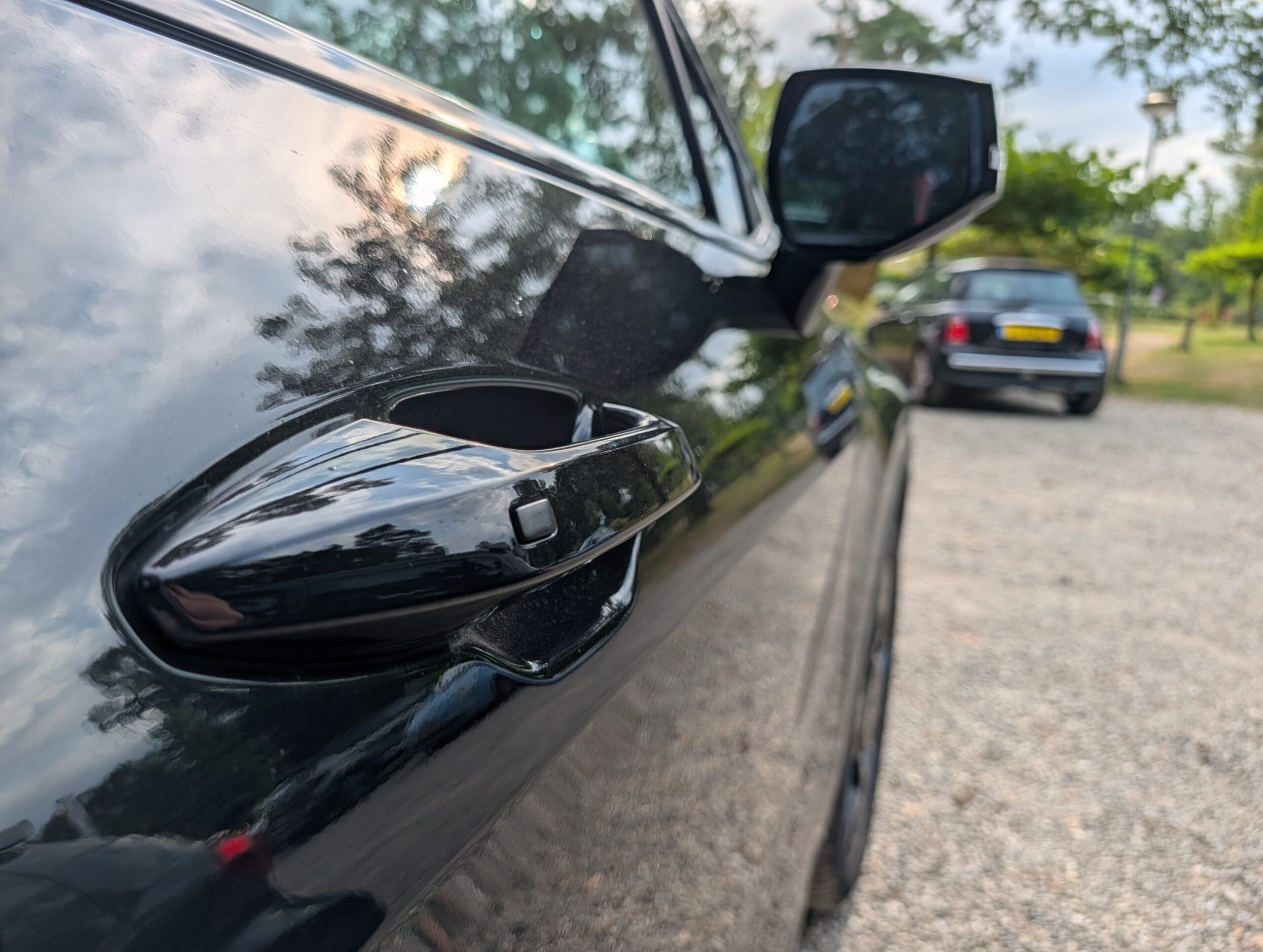 Close-up van de zijkant van de zwarte Kia Sportage met de zwarte deurgreep en zijspiegel