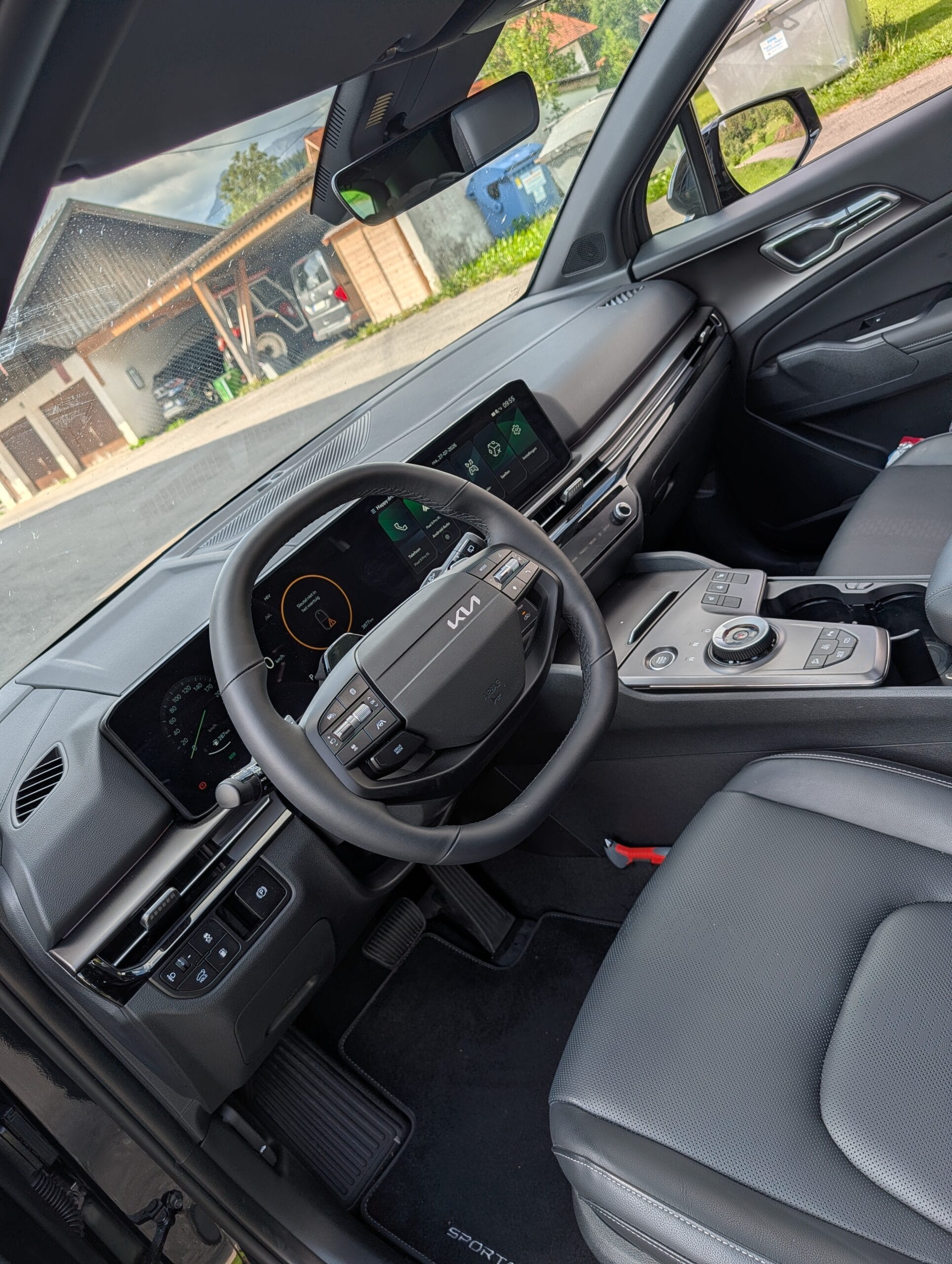 Interieur van de Kia Sportage met het stuurwiel, de digitale displays op het dashboard en de middenconsole