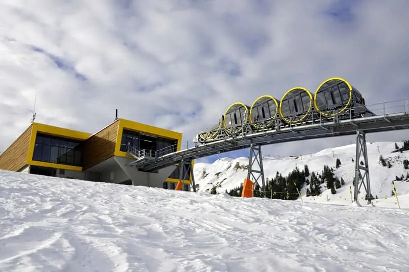 De Stoosbahn-kabelbaan met zijn kenmerkende ronde gele cabines op een steile helling in een besneeuwd berglandschap